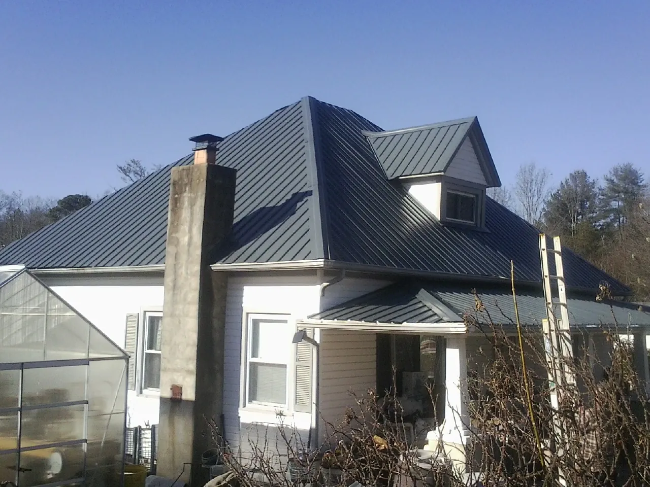 Dark blue standing seam metal roof on a white farmhouse with dormer — Slate & Tile Roof Repair by Roofing Brothers in Braceville