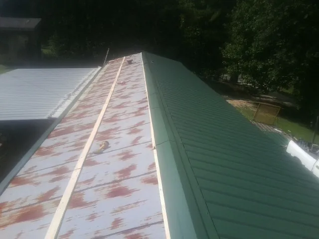 Old rusted panels beside newly installed green metal roofing — Wind Damage Roof Repair by Roofing Brothers in Braceville