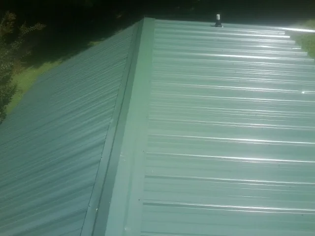 New green metal panels meeting at the ridge of a roof — Flat Roof Repair work by our crew in Braceville