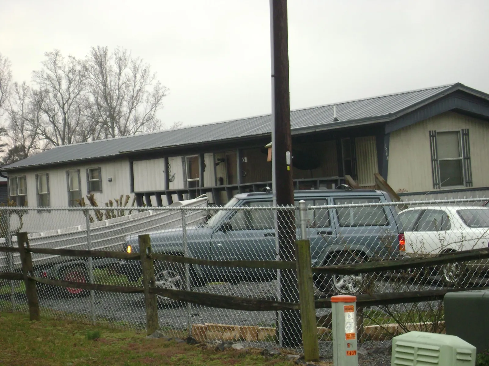 Dark metal roof on a long single story building behind a chain link fence in Braceville