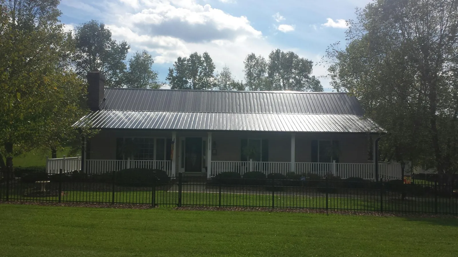 Gray metal roof on a brick ranch with a full width front porch — Gutter Guard Installation work by our crew in Braceville