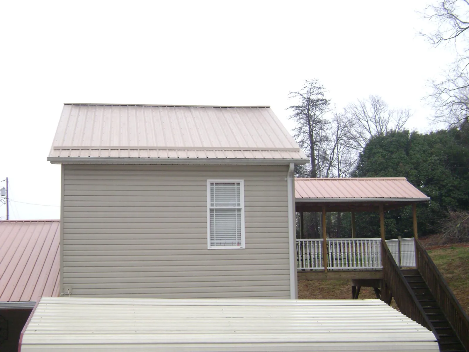 Tan metal roofs on a two story addition and attached porch, from a Roof Replacement job in Braceville