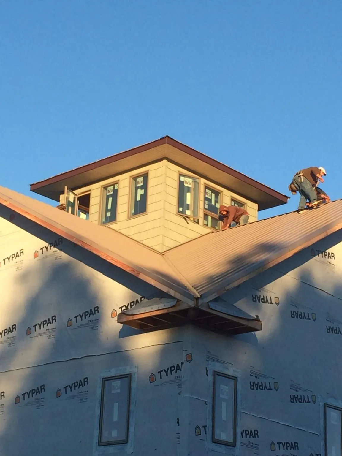 Roofers working around a rooftop cupola on a new metal roof at sunset — Roof Waterproofing in Braceville by Roofing Brothers
